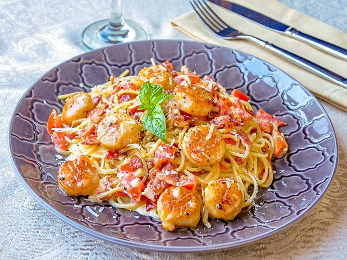 Creamy Garlic Scallop Spaghetti with Bacon wide shot photo of a single serving on a grey patterned plate