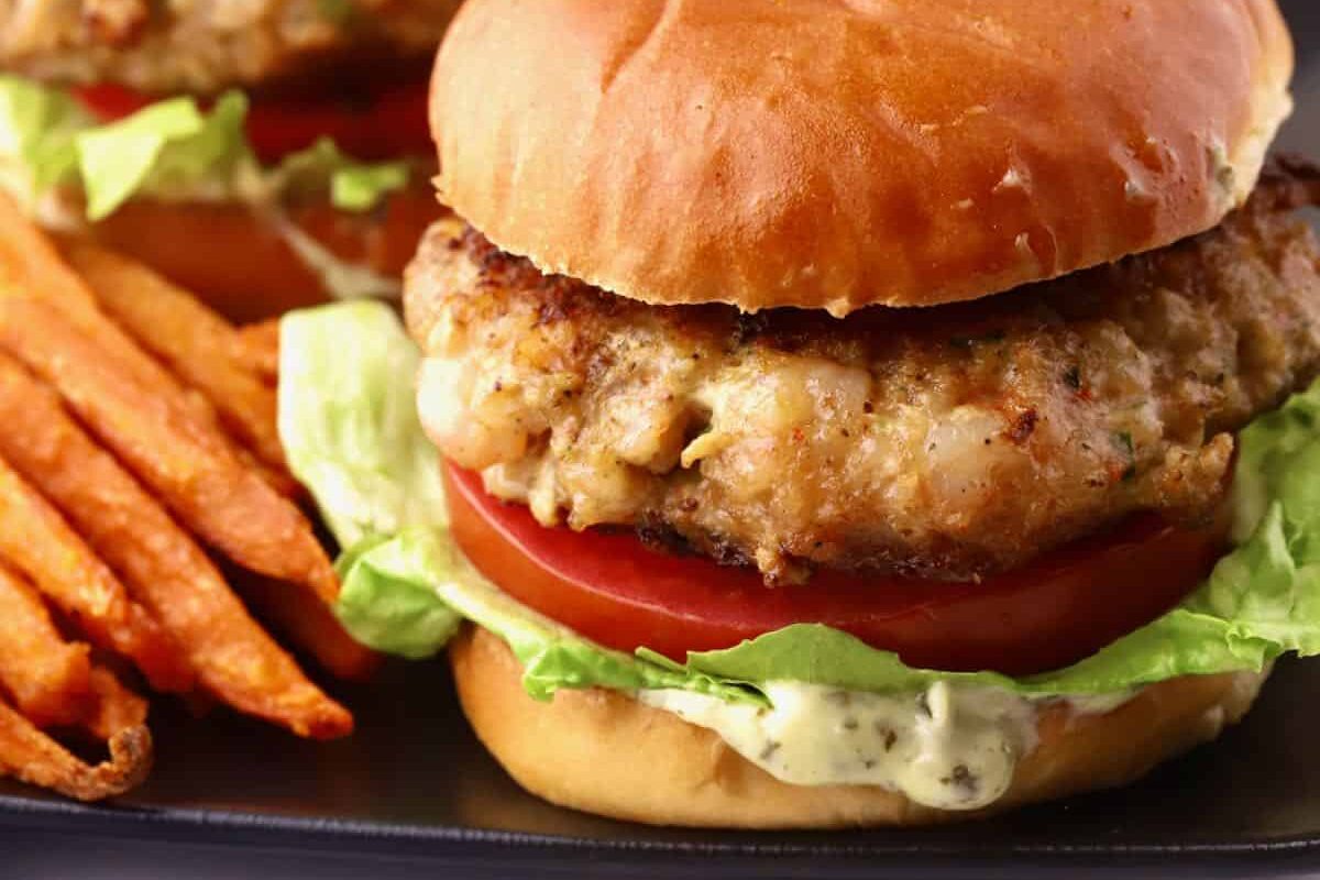 Two shrimp burgers with lettuce and tomato.