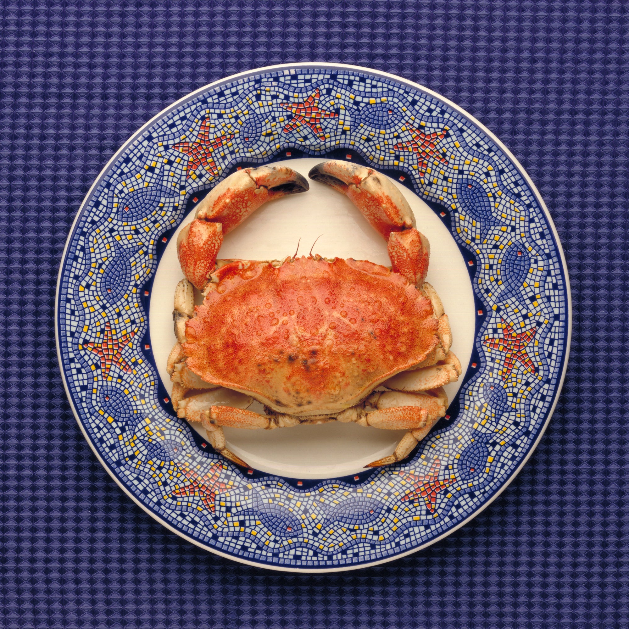 A plate of crab meat salad with vegetables and avocado, garnished with fresh herbs.