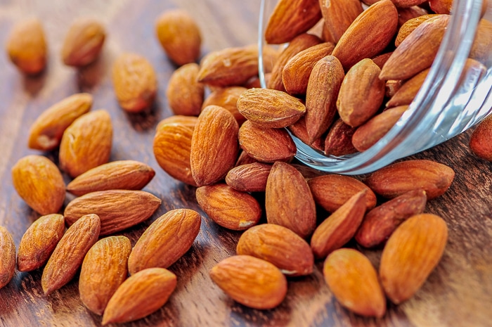 Roasted almonds spilling out of small glass bowl
