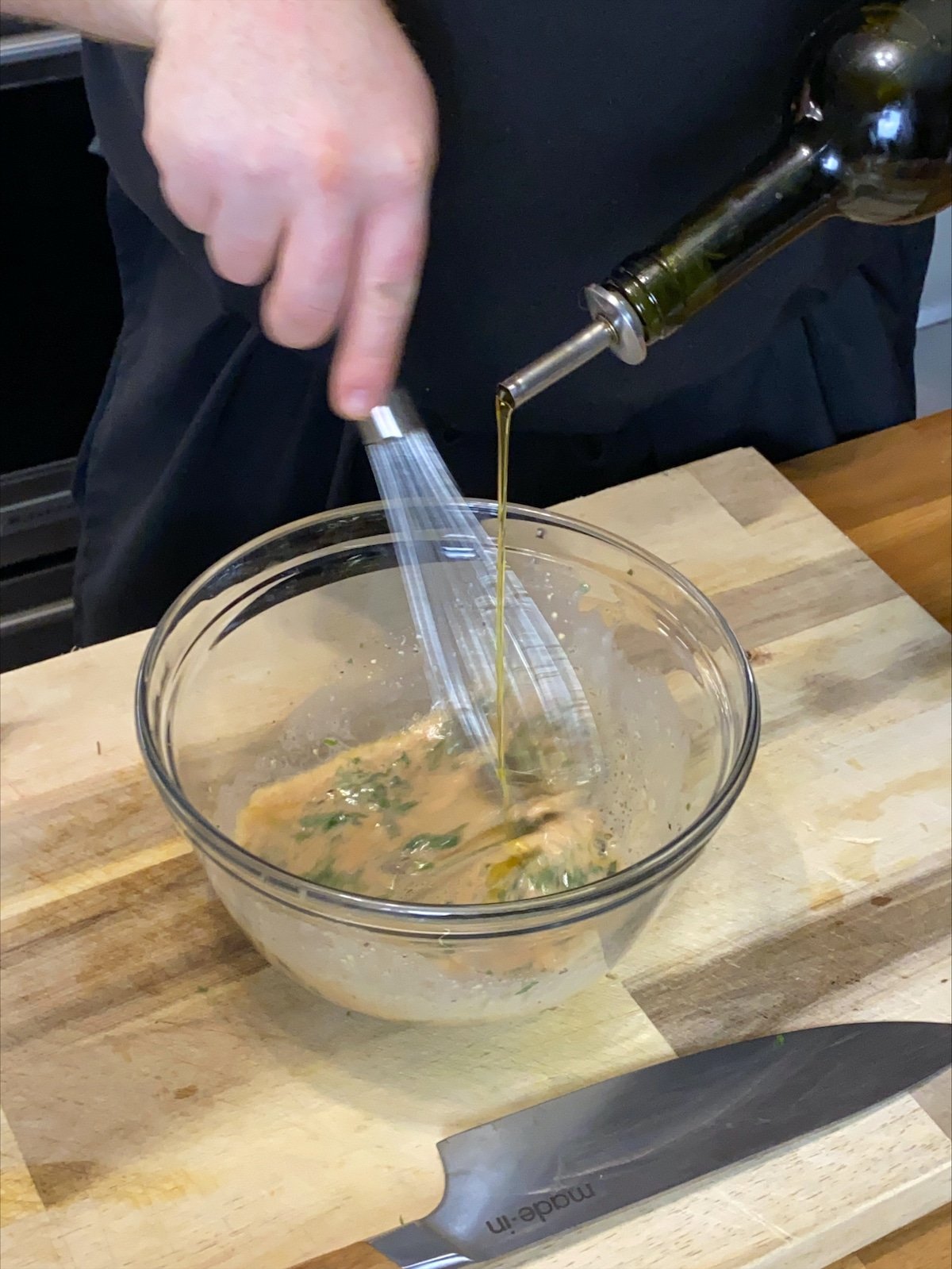 Whisking the oil into the vinaigrette.