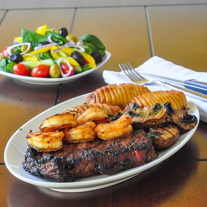 Honey Ginger Soy Surf and Turf with hasselback potatoes and mushrooms on a white plate