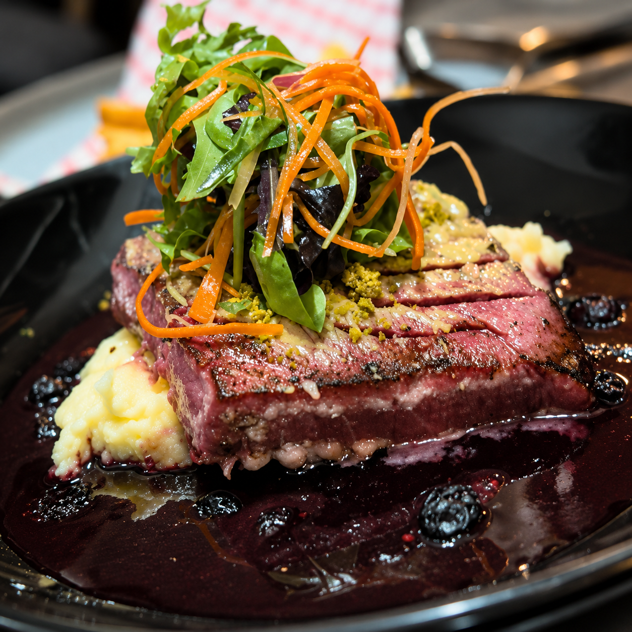 Perfectly seared tuna medallions plated over creamy mashed potatoes with blueberry reduction sauce, crushed pistachios, and fresh mixed greens in a fine dining seafood presentation inspired by Nuevo Vallarta cuisine.