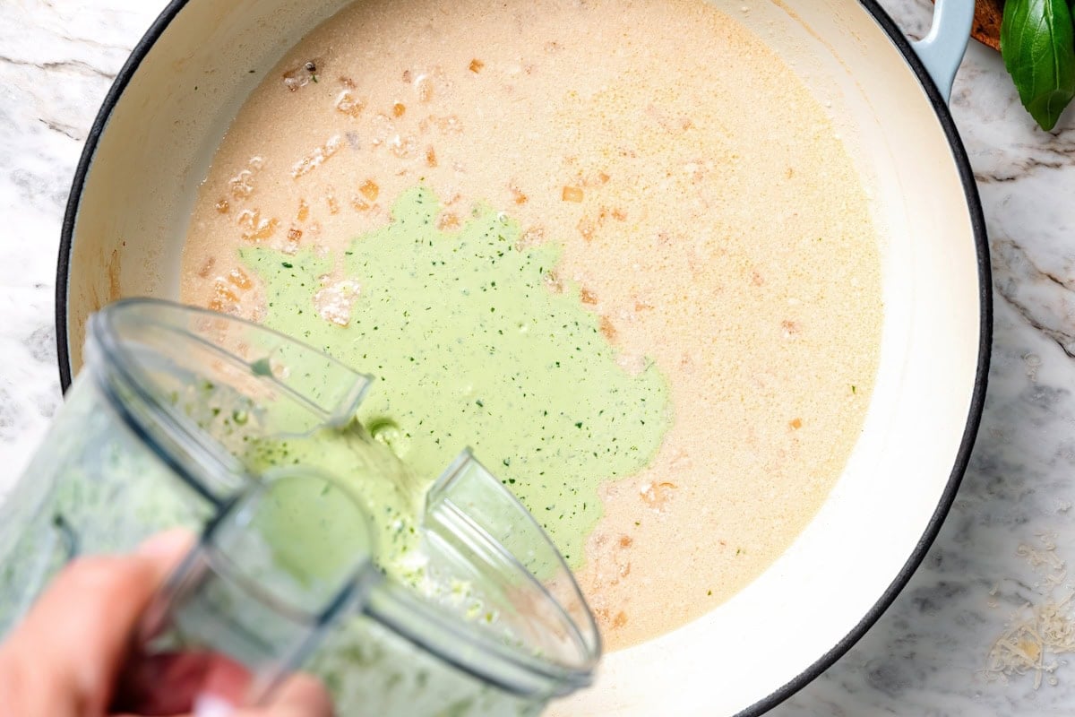Pouring basil cream sauce into pan.