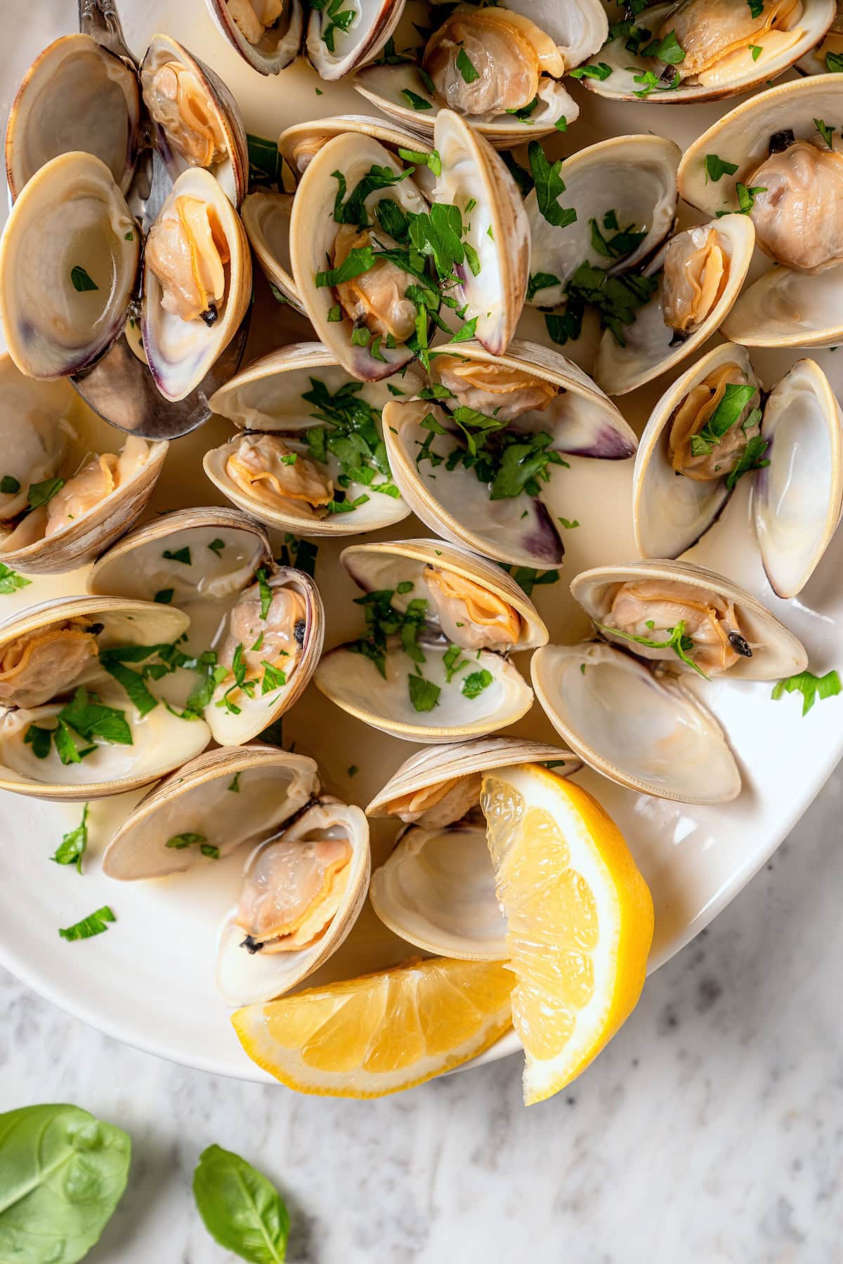 These steamed clams are flavorful and surprisingly easy. With a garlicky white wine broth, they're lighter than the restaurant version too! Platter of steamed clams with lemon wedges.