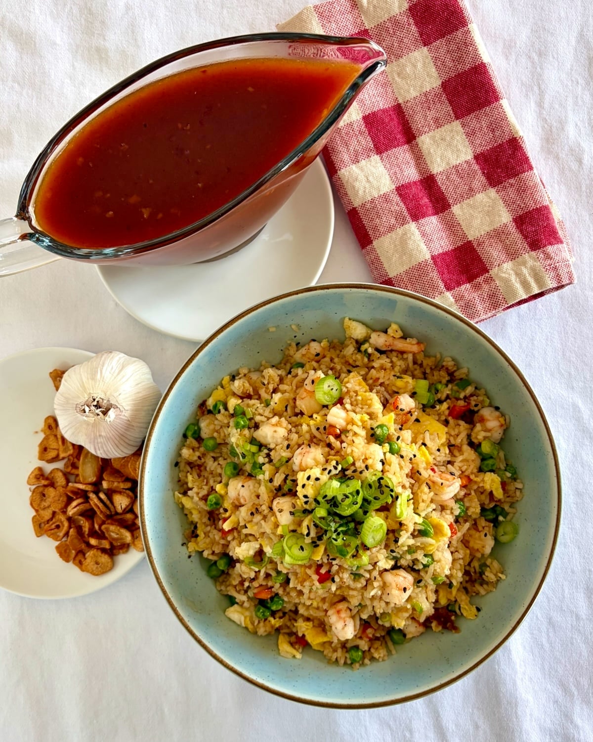 Overhead photo of Shrimp Fried Rice with Sweet and Sour Sauce and Crispy Garlic on the side.