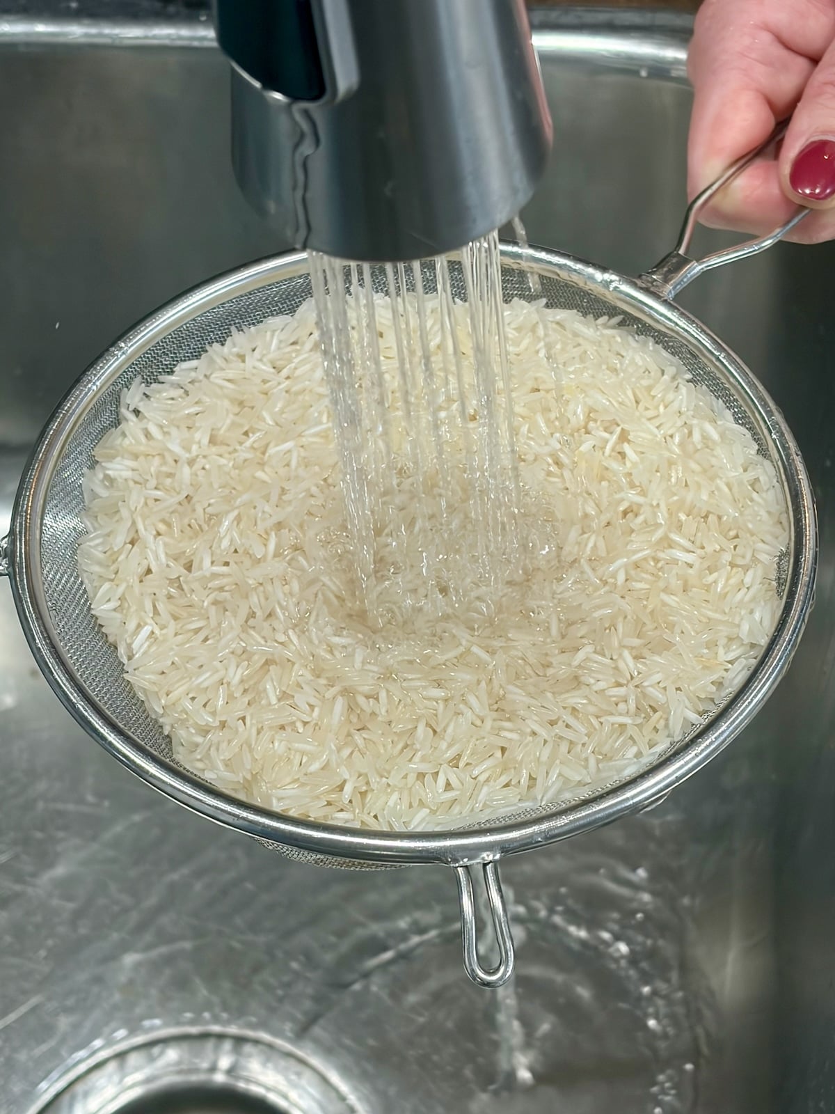 Photo of rice being rinsed in a sieve.